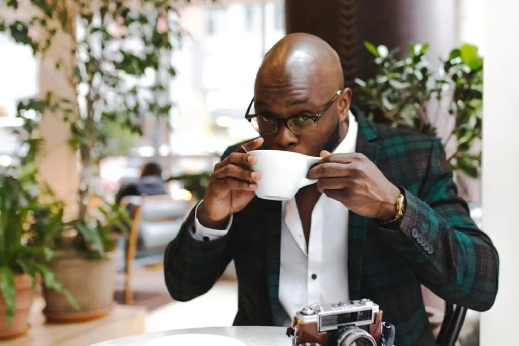 A bald man with glasses and drinking a cup of coffee