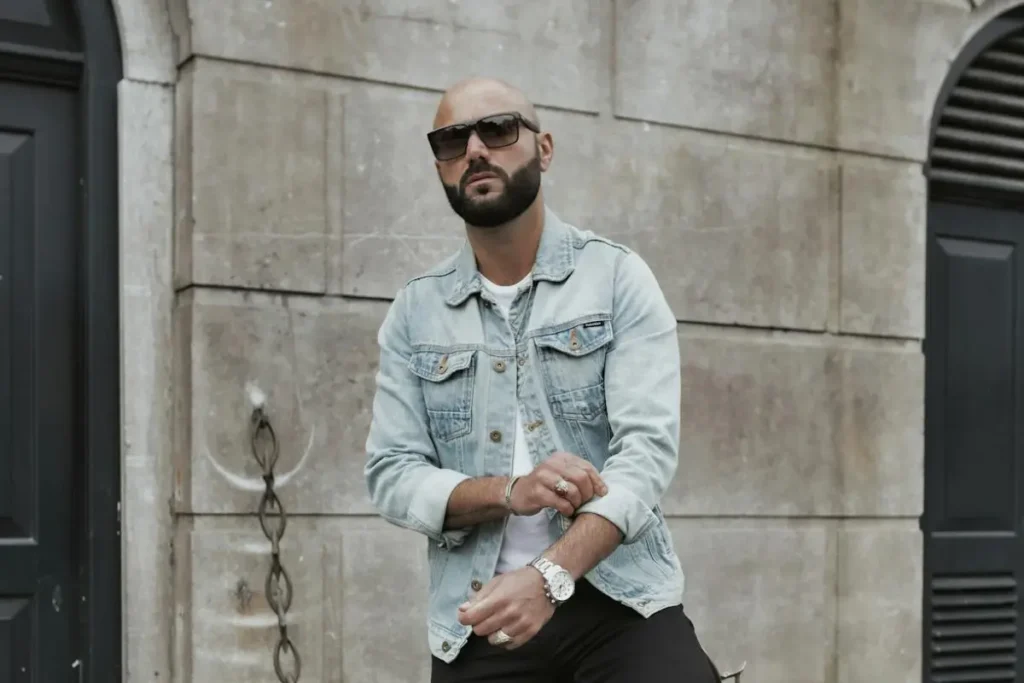 a man with a shaved head, sunglasses and a watch