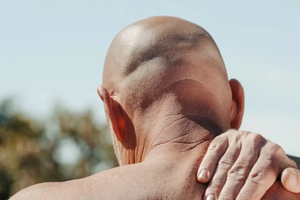 the shaved head of a man standing on his back