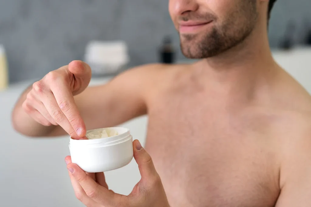 A man taking cleanser or moisturizer product out of a plastic jar