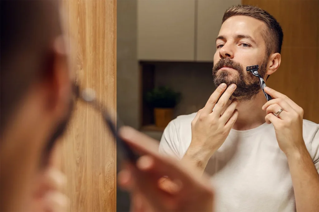 a man styling his beard in front of the mirror