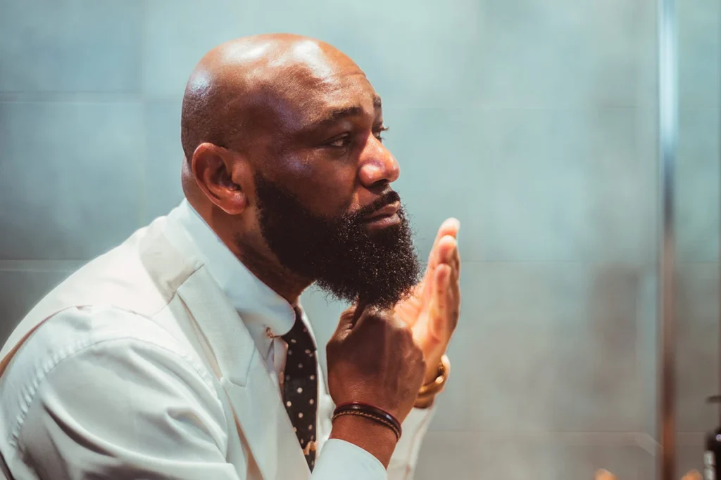 Bald man in shirt and tie styles his beard