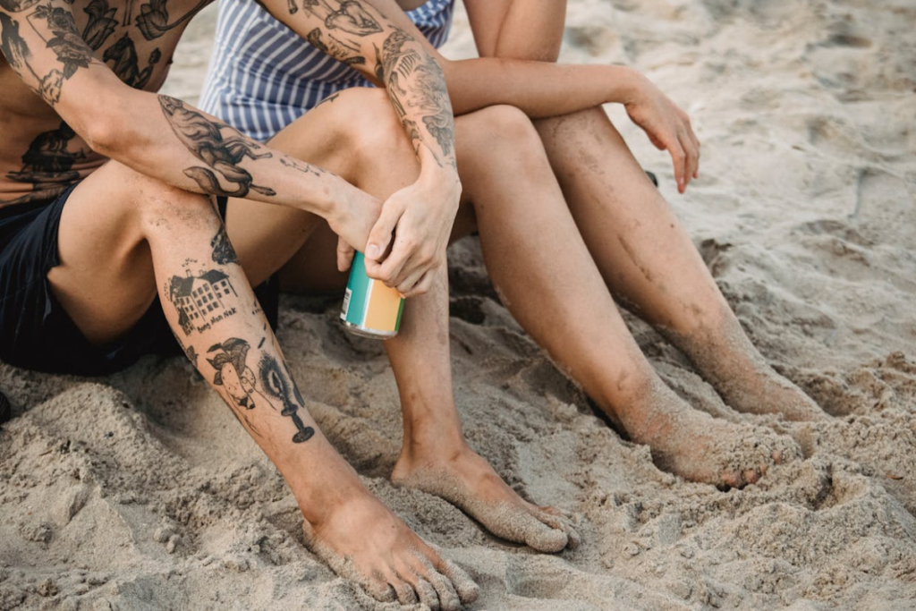 two people on the beach one with tattoos